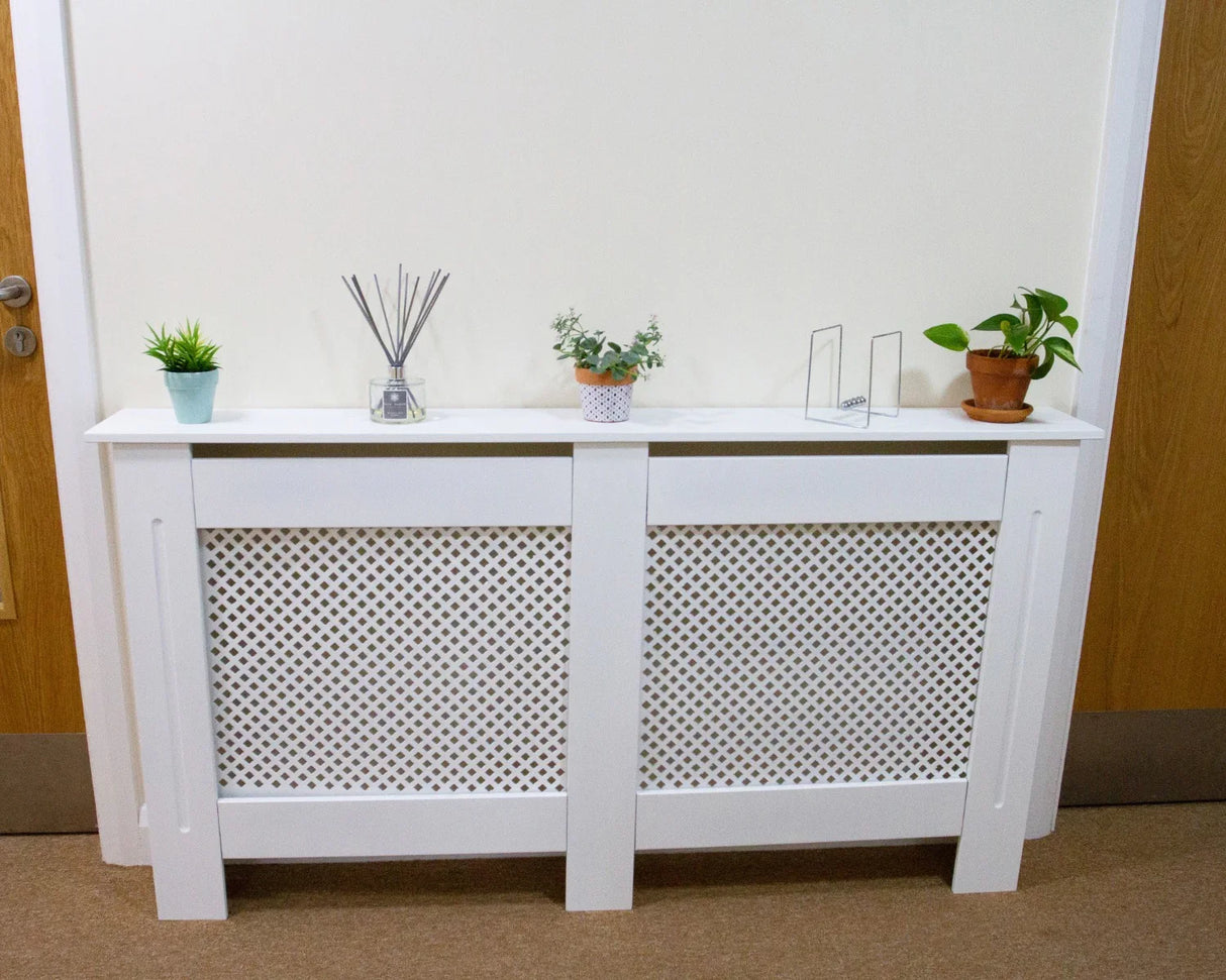 White MDF radiator cover with decorative lattice design, styled with potted plants and decorative items on top, enhancing interior decor