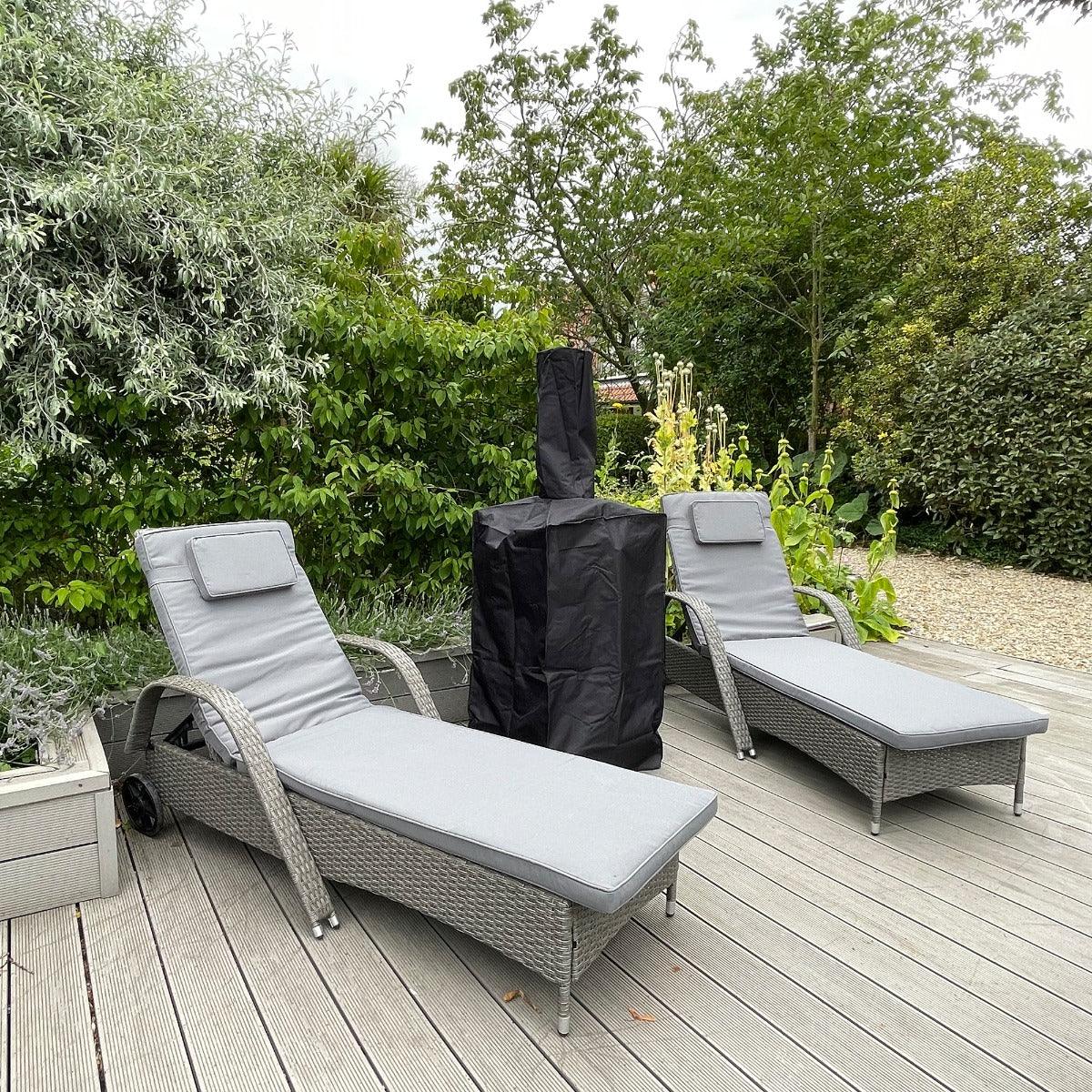Kukoo outdoor pizza oven rain cover in black, fitted over the oven, surrounded by lounge chairs on a wooden deck with greenery