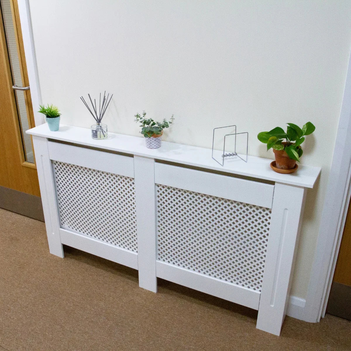 Unfinished MDF radiator cover, 1115mm wide, featuring a decorative lattice design, styled with potted plants and decorative items