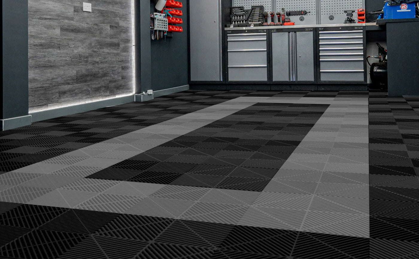 Stylish black and gray interlocking floor tiles with a textured geometric pattern, enhancing a modern garage workspace