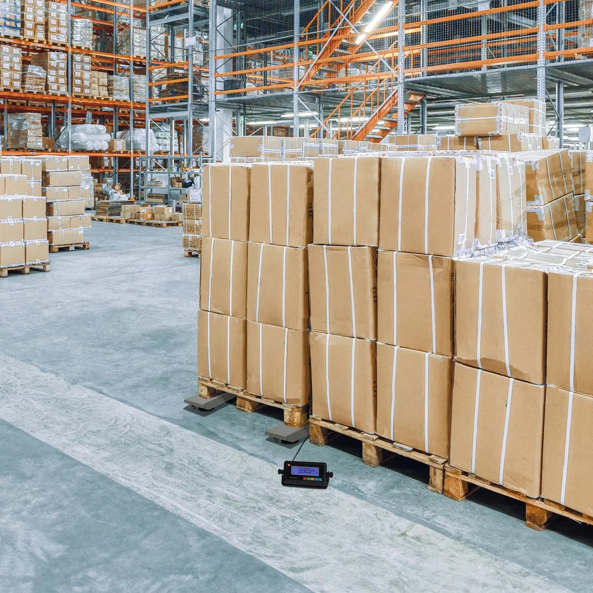 T-Mech Industrial Weighing Beam Scales positioned on a warehouse floor, surrounded by neatly stacked cardboard boxes on pallets