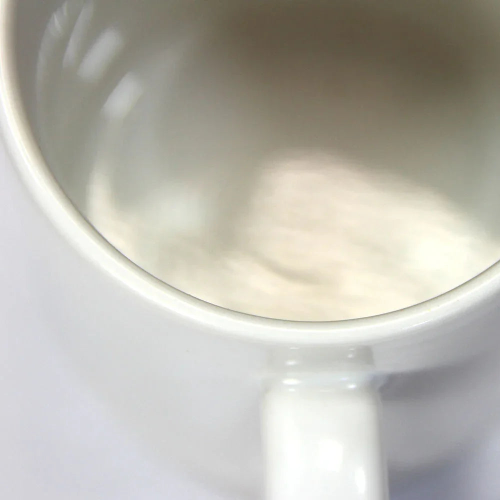 Close-up of glossy white polymer-coated ceramic mug with wide rim and sturdy handle.