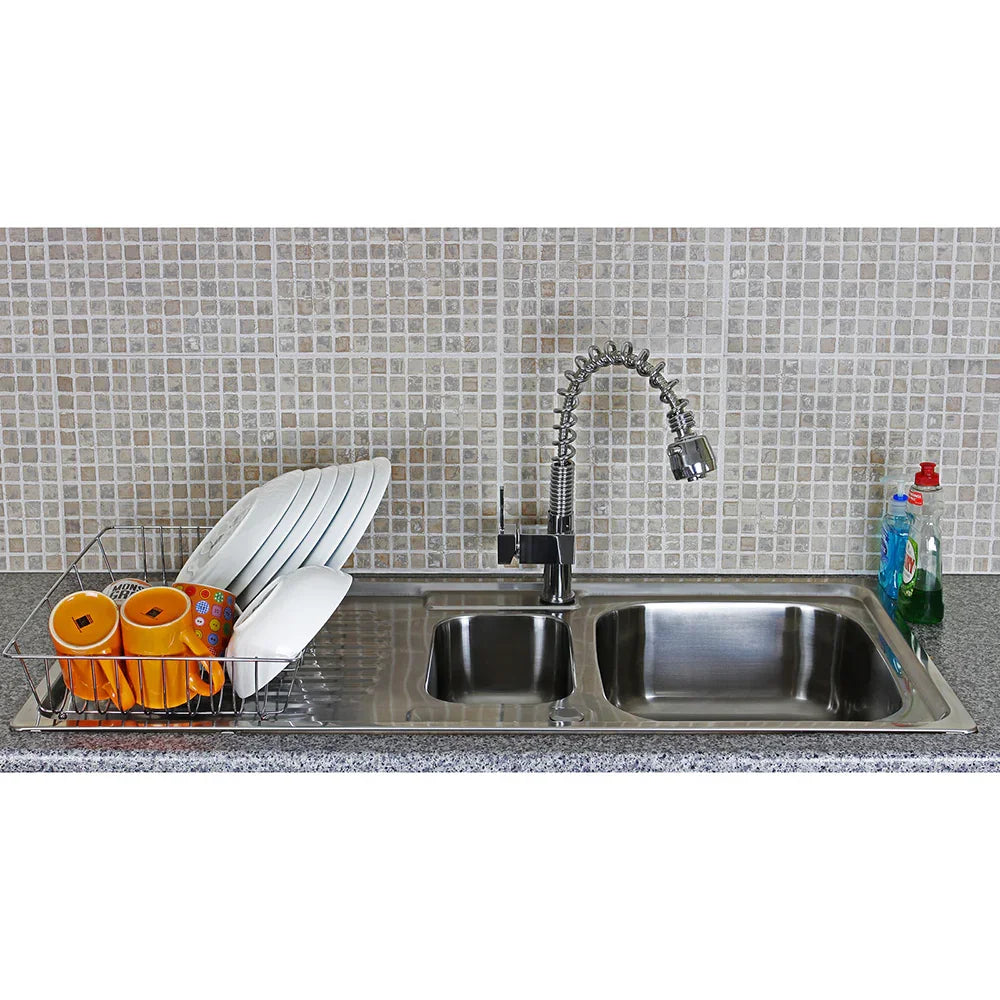 Premium stainless steel kitchen sink with a sleek Padstow tap, featuring stacked plates, colorful cups, and dish soap on a granite countertop