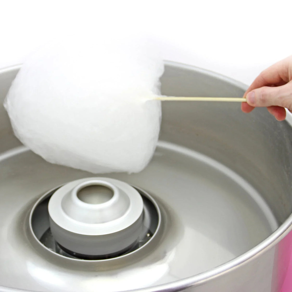 Fluffy white cotton candy being pulled from the KuKoo Candy Floss Making Machine, showcasing its shiny stainless steel bowl and central spinner
