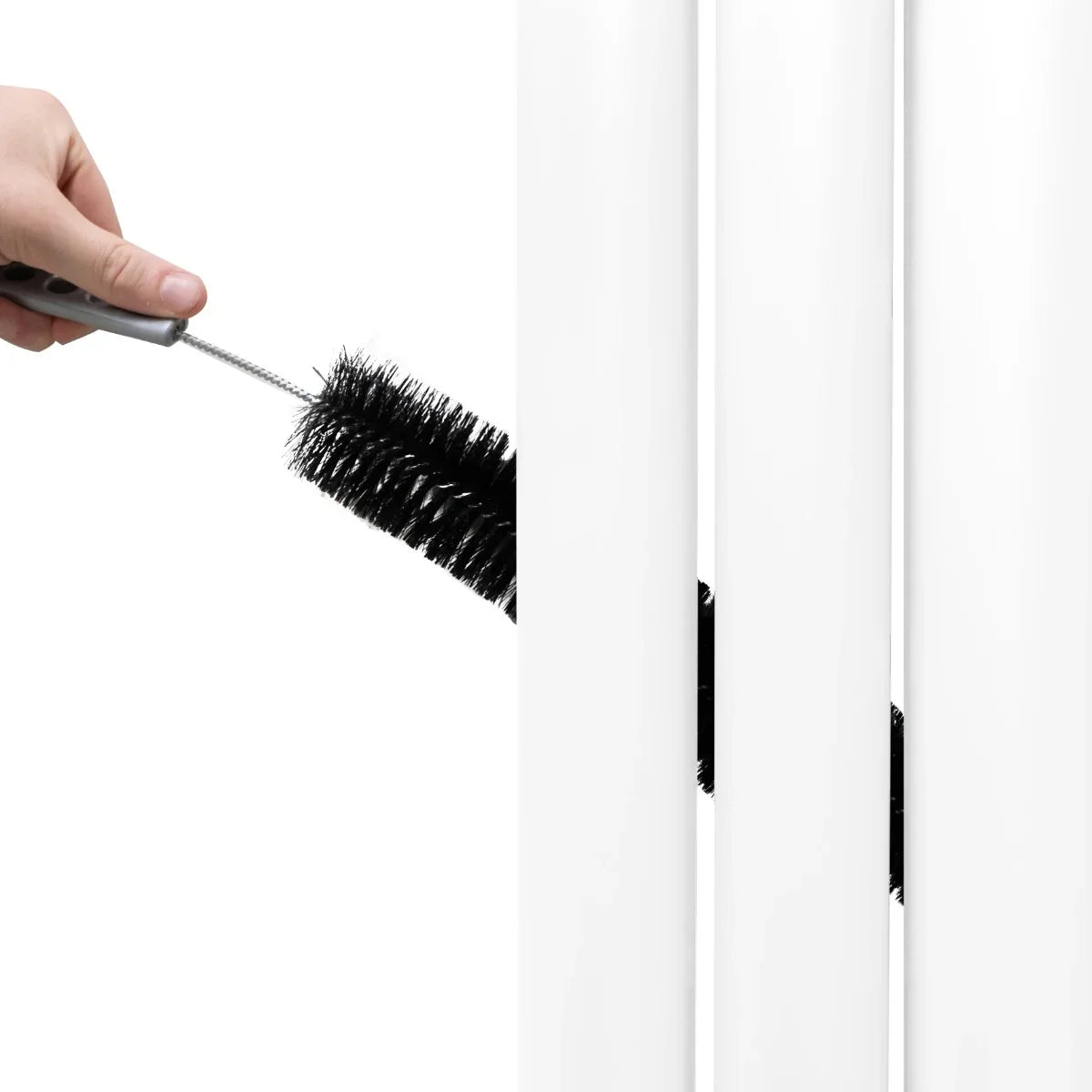 White oval mirror radiator with a hand using a cleaning brush, showcasing its sleek design and easy maintenance features