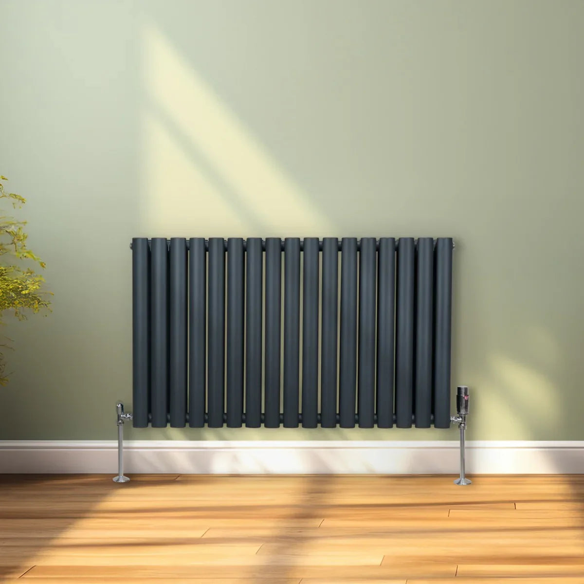 Oval column radiator in anthracite grey, 600mm x 1020mm, featuring vertical slats and sleek valves, set against a light green wall