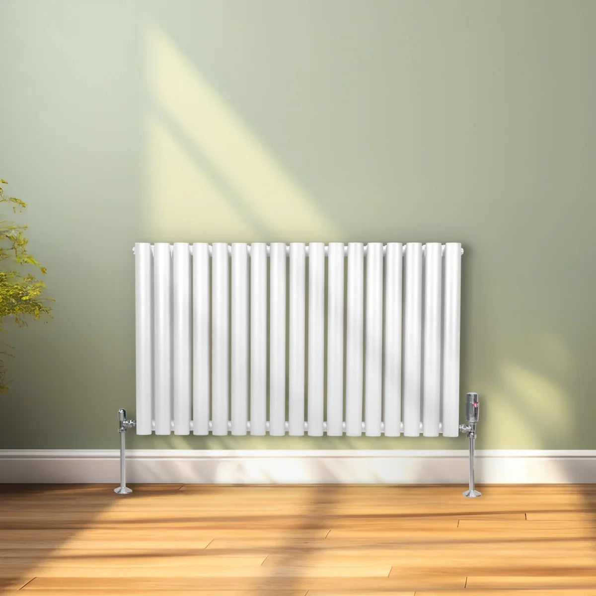 White oval column radiator with vertical fins and valves, mounted on a wall, casting soft shadows on a wooden floor