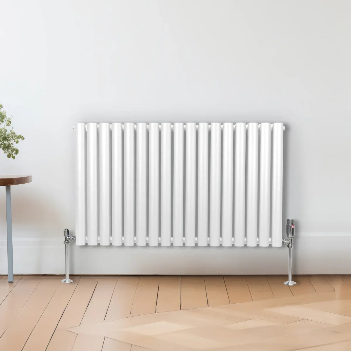 White oval column radiator with vertical fins, measuring 600mm x 1020mm, mounted on the wall in a modern interior setting