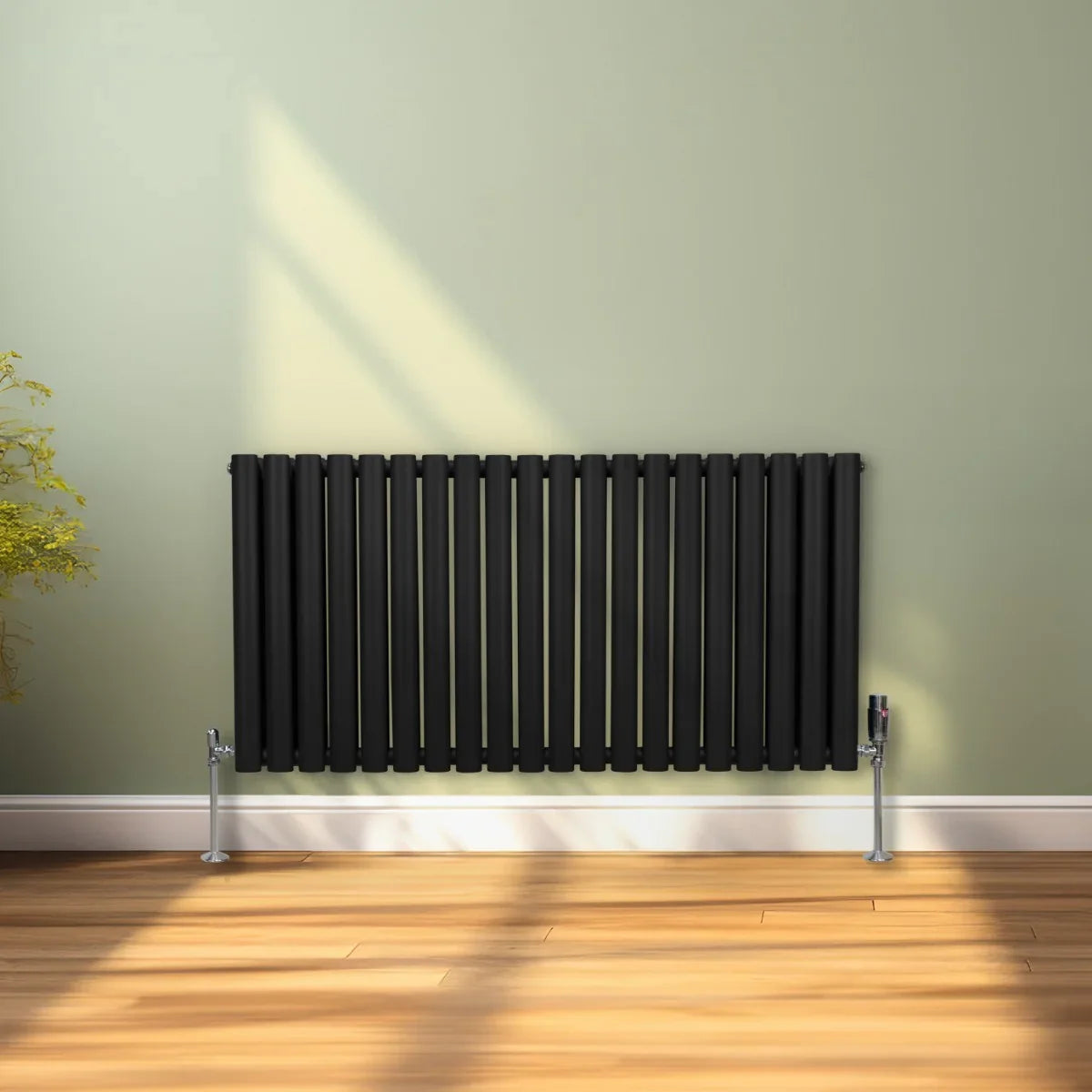 Sleek black oval column radiator with vertical bars, measuring 600mm x 1200mm, mounted on silver valves against a light green wall