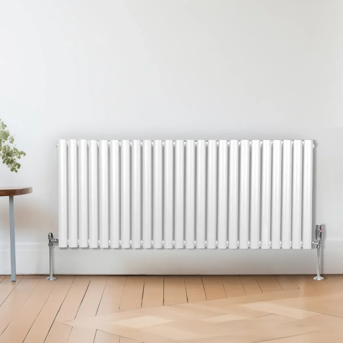 White oval column radiator with vertical fins, 600mm x 1440mm, mounted on the wall above light wooden flooring, complemented by chrome valves