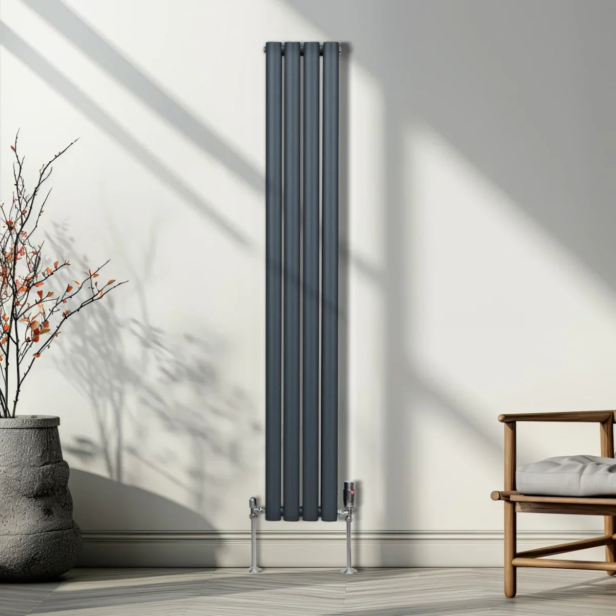 Anthracite grey oval column radiator with sleek vertical lines, mounted on a wall, complemented by modern chrome valves and natural light shadows