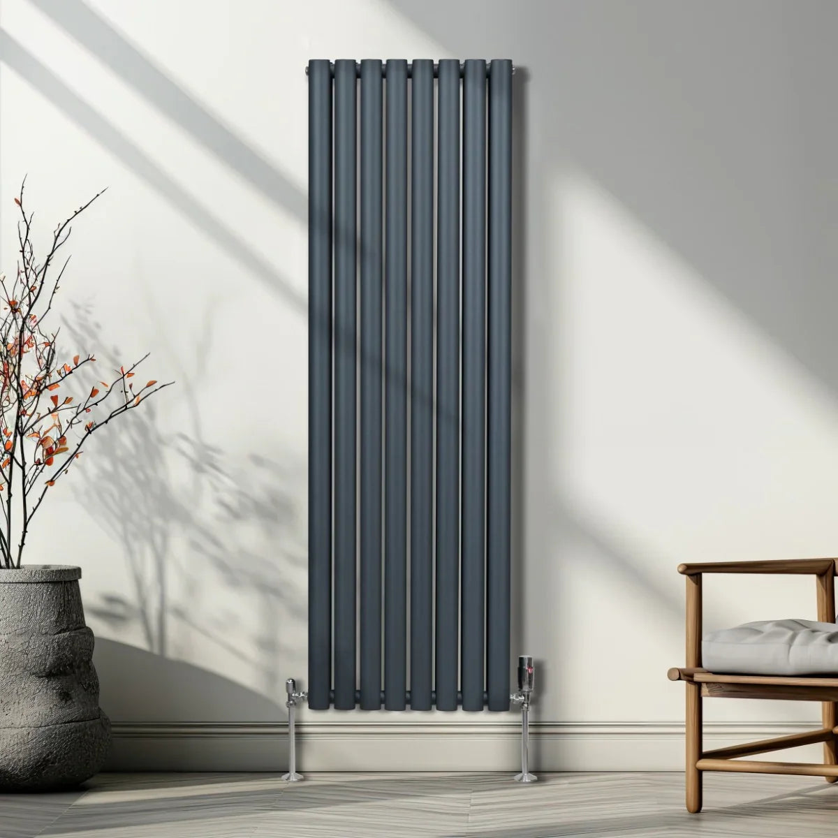 Anthracite grey oval column radiator with sleek vertical lines, mounted on a wall, complemented by modern valves and a minimalist setting
