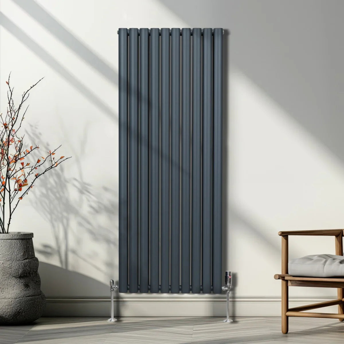 Oval column radiator in anthracite grey, featuring vertical slats and sleek valves, set against a minimalist interior backdrop