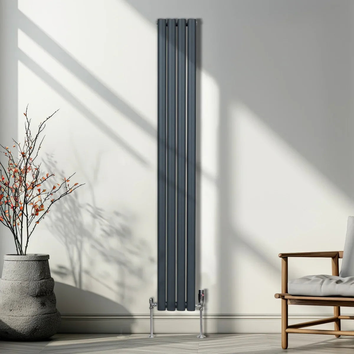Anthracite grey oval column radiator with sleek vertical design, mounted on chrome valves, set against a bright, modern interior