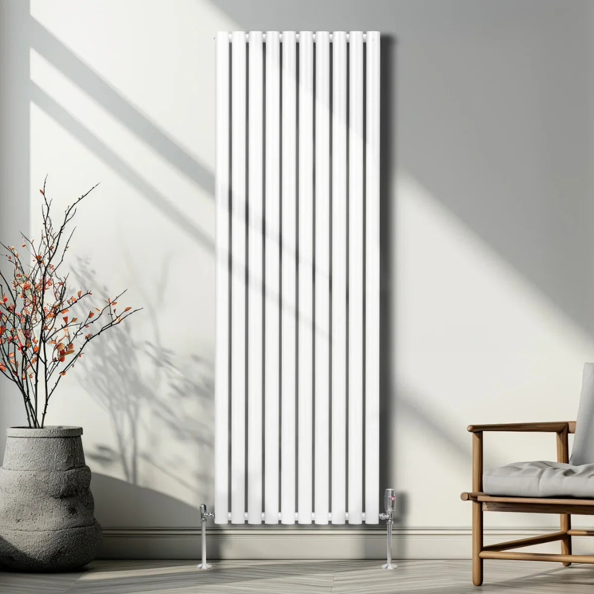 Sleek white oval column radiator with vertical fins, standing tall in a modern room beside a decorative plant and chair