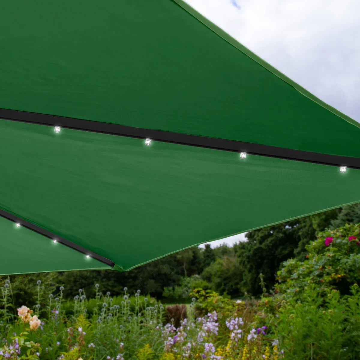 Green 3m LED cantilever parasol with a sleek design, featuring integrated lights and a sturdy base, set against a vibrant garden backdrop