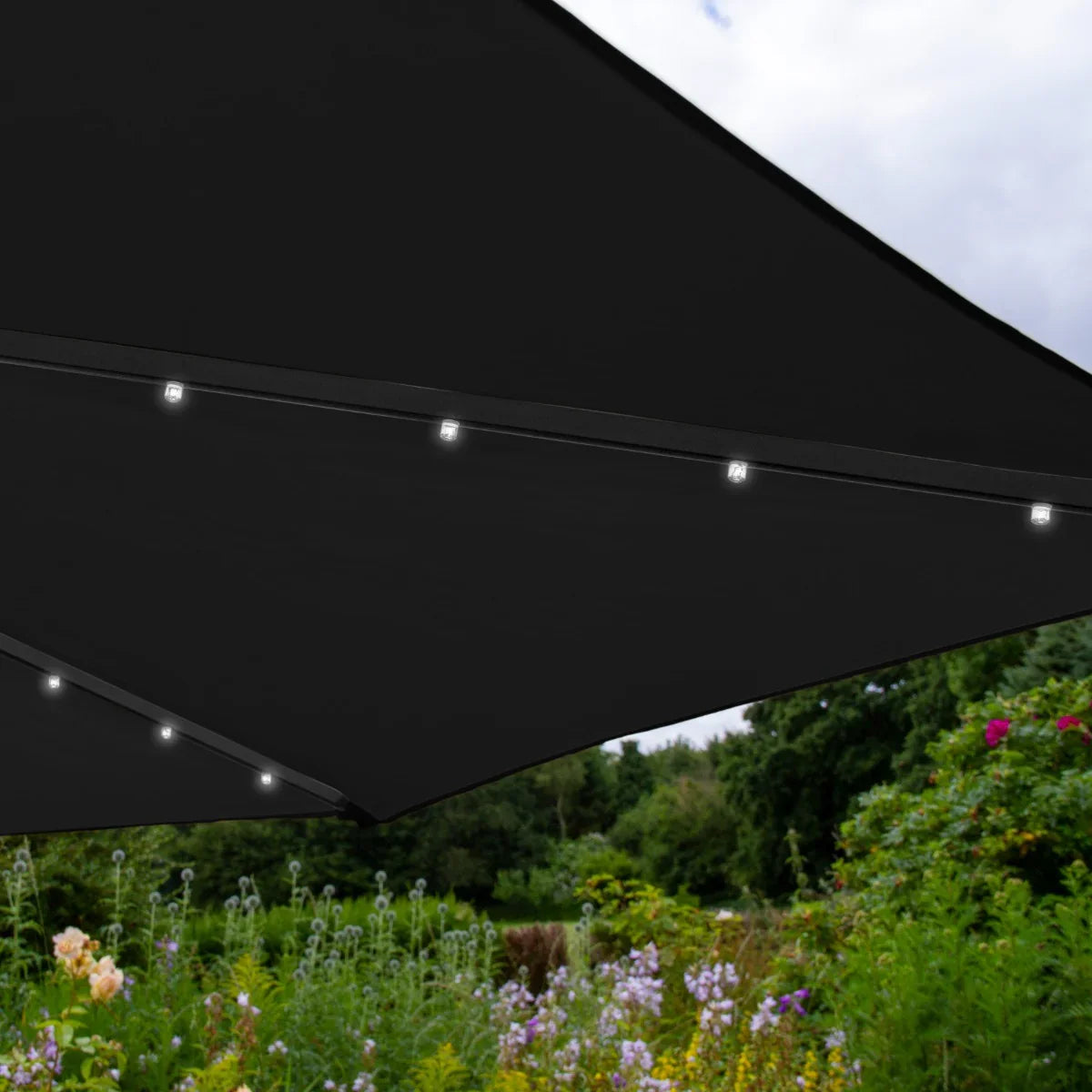 Black 3m LED cantilever parasol with integrated lights, showcasing a sleek design against a vibrant garden backdrop
