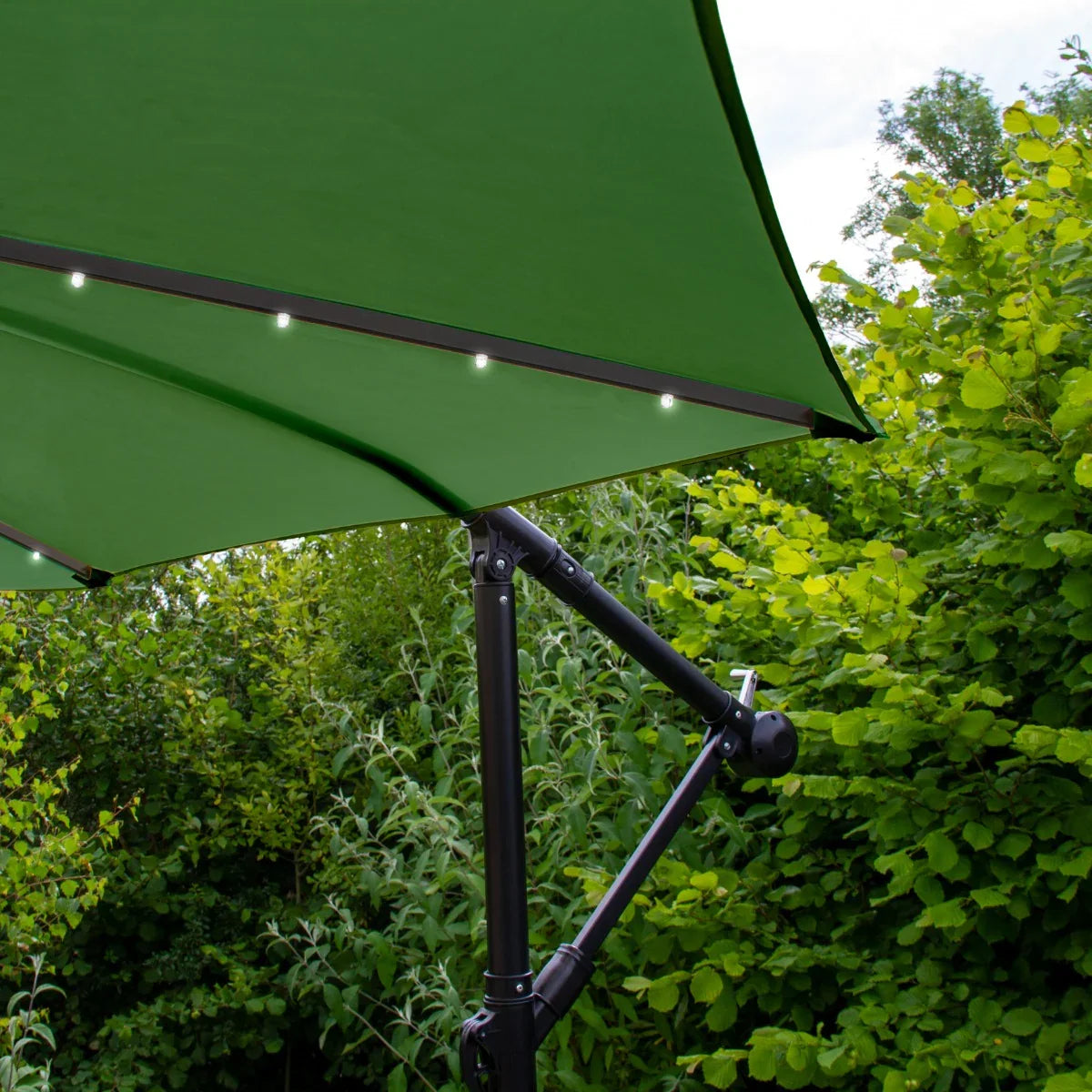 Green 3m LED cantilever parasol with a sturdy fan base, featuring a sleek design and integrated lights under the canopy