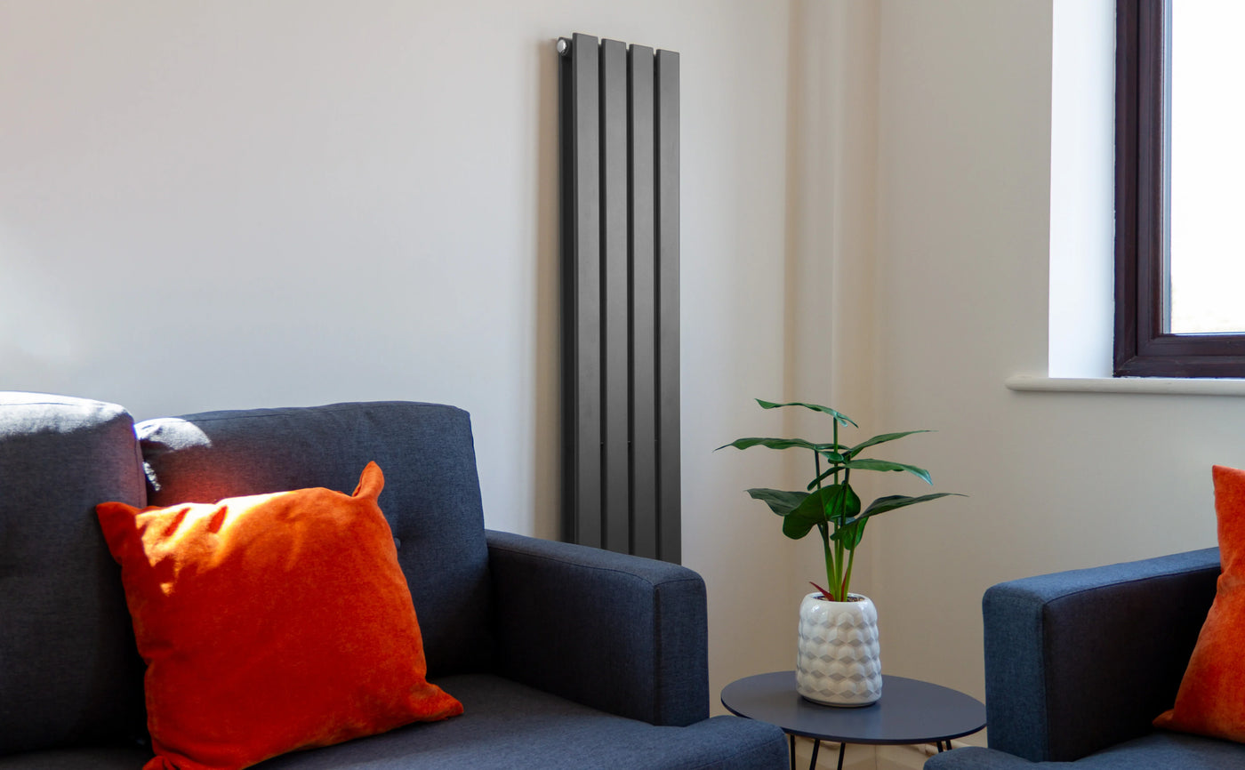 Modern living room featuring a sleek black radiator, gray sofas with orange cushions, and a small potted plant on a side table