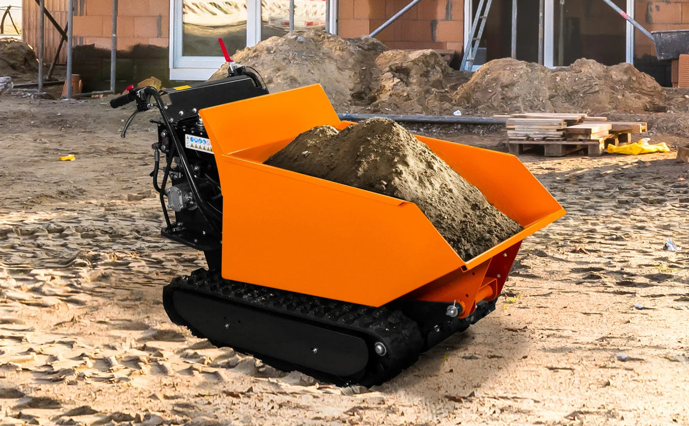 Compact orange tracked dumper filled with sand, set on a construction site with a sandy ground and building materials in the background