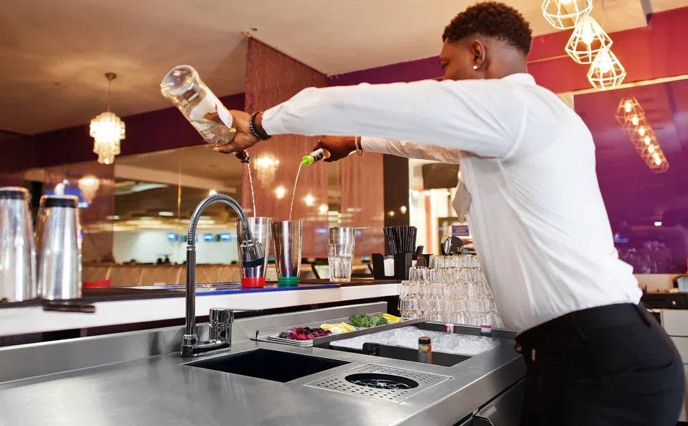 Bartender in a white shirt skillfully pours liquor into a shaker, surrounded by fresh ingredients and modern bar equipment