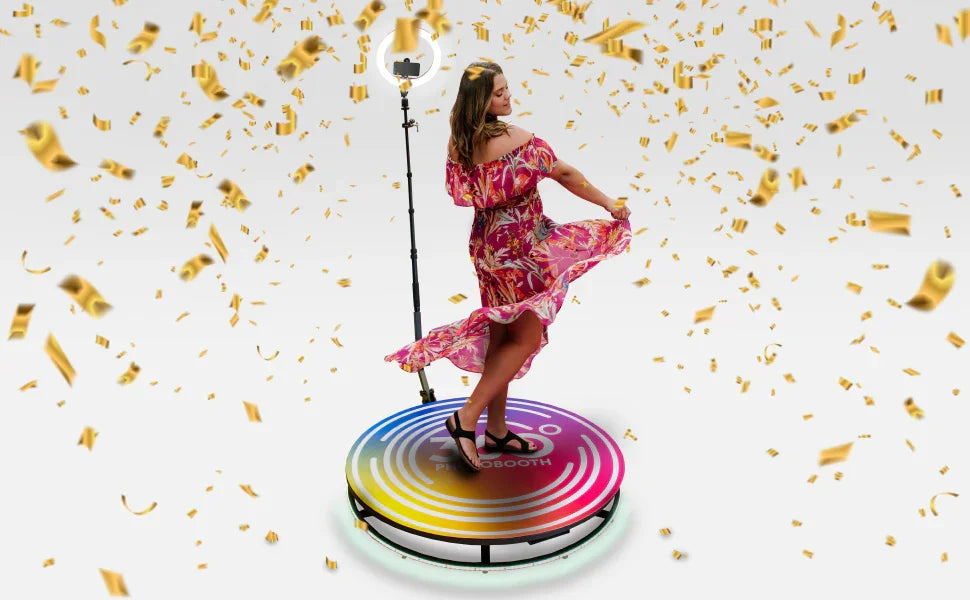 A woman in a vibrant floral dress twirls on a colorful photo booth platform, surrounded by golden confetti and soft lighting