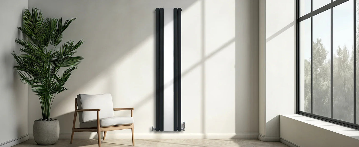 Modern black vertical radiator mounted on a light wall, beside a cozy beige armchair and a lush green potted plant in a sunlit room