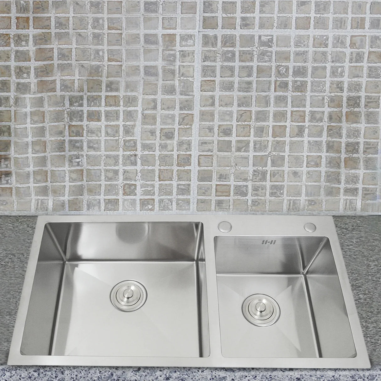 Double stainless steel sink with two compartments, featuring a sleek design, polished finish, and modern drain covers, set against a mosaic tile backdrop