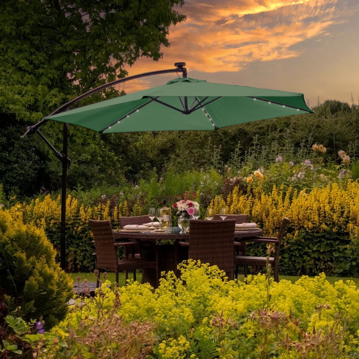 Green 3m LED cantilever parasol with a sturdy black frame, casting shade over a garden dining table surrounded by vibrant flowers