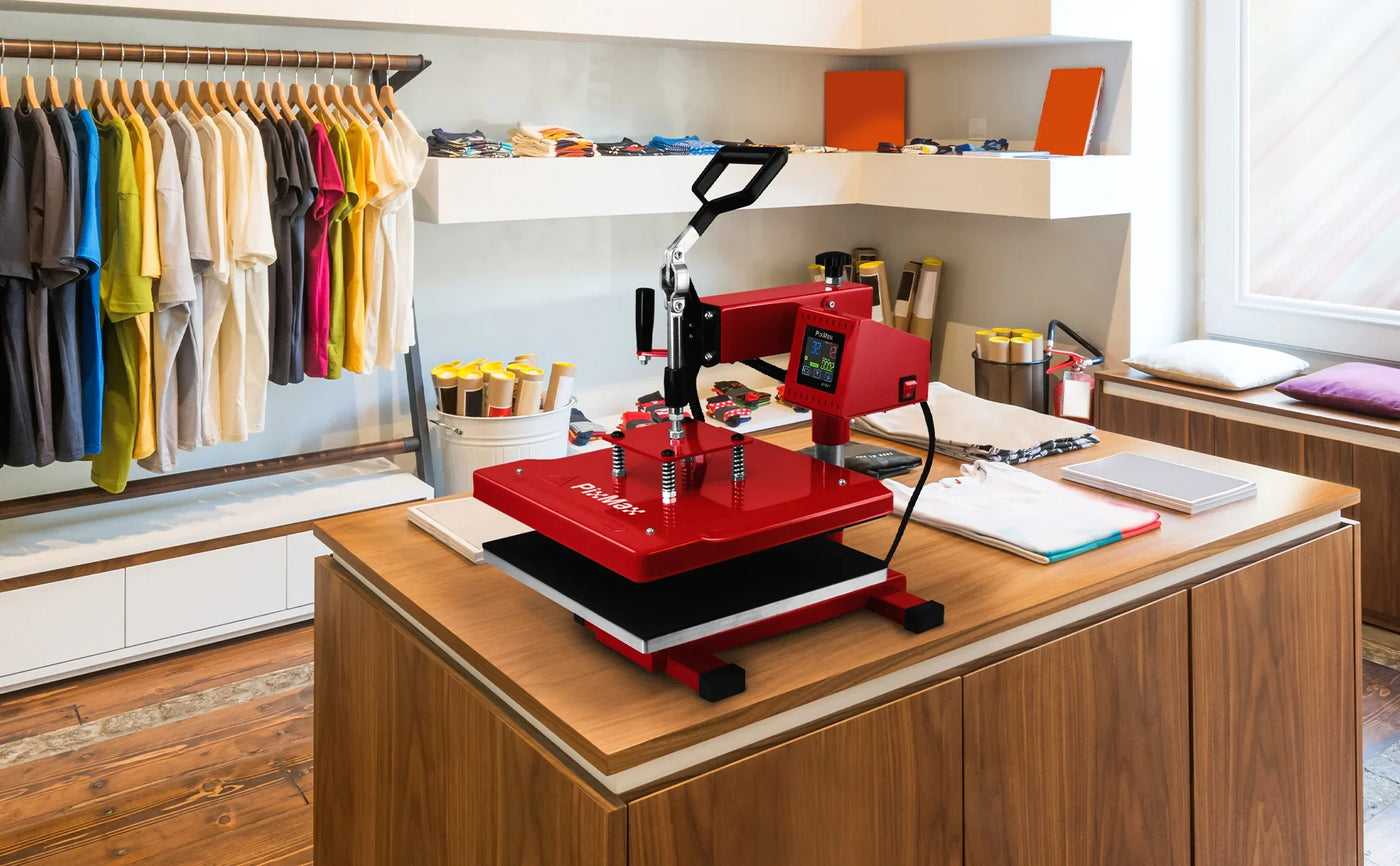 Red heat press machine on a wooden table, surrounded by colorful t-shirts and craft supplies in a bright, modern workspace