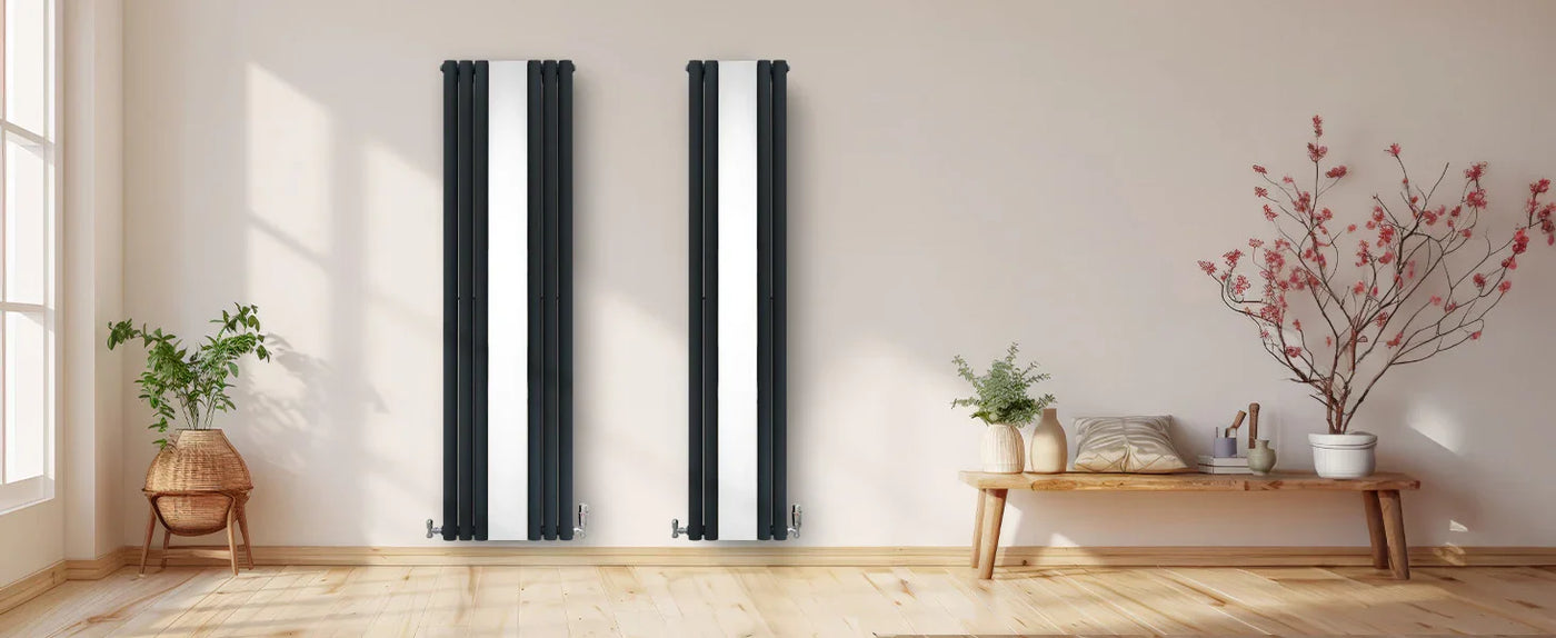 Modern black vertical radiators against a light wall, complemented by a wooden bench, potted plants, and decorative branches