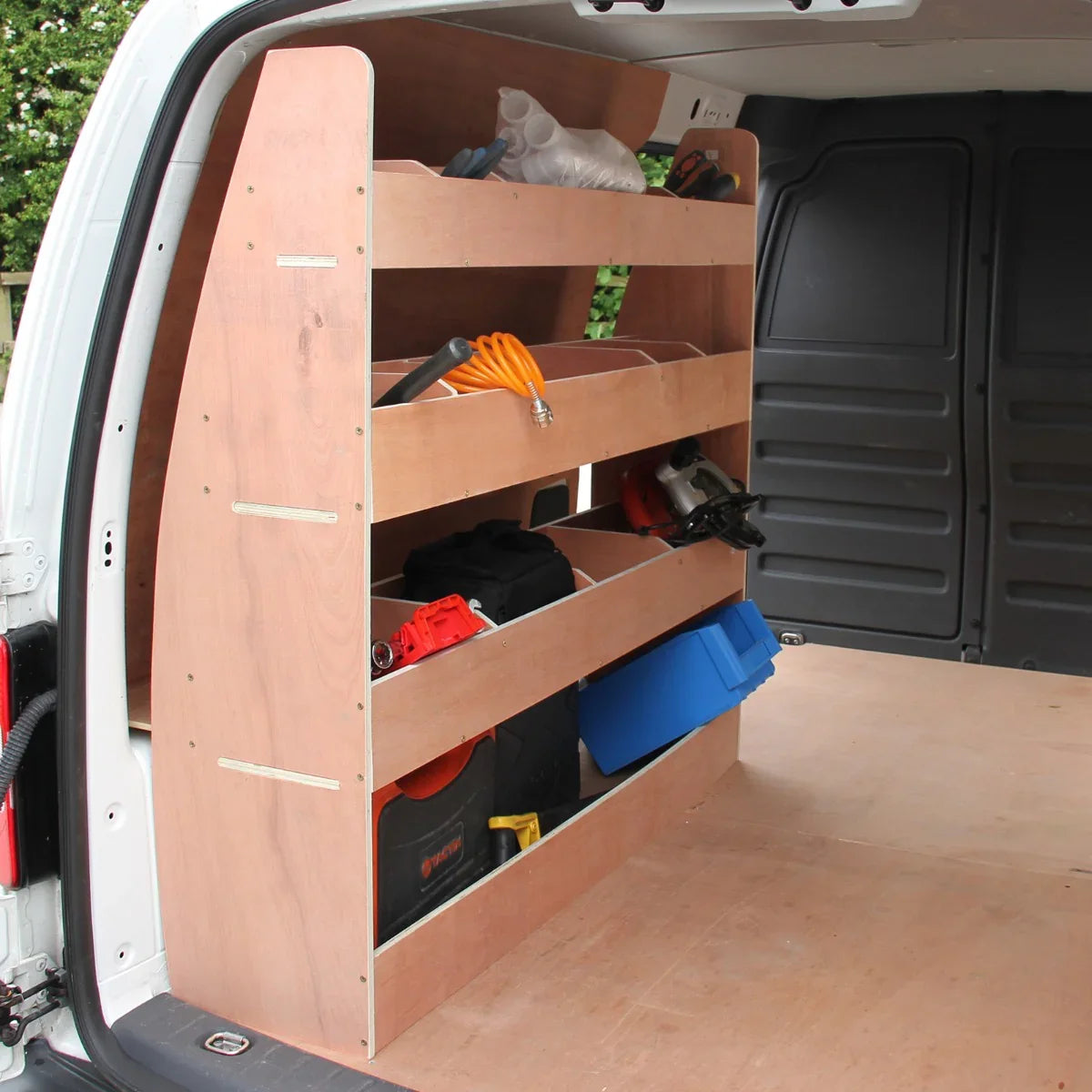Silver van lining with wooden racking unit featuring multiple shelves, tools, and storage bins inside a VW Caddy van