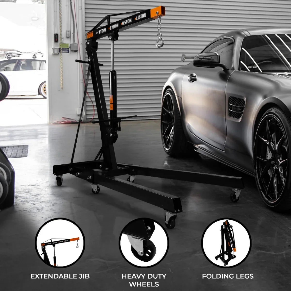 Hydraulic engine crane with extendable jib, heavy-duty wheels, and folding legs, set against a sleek car in a garage environment