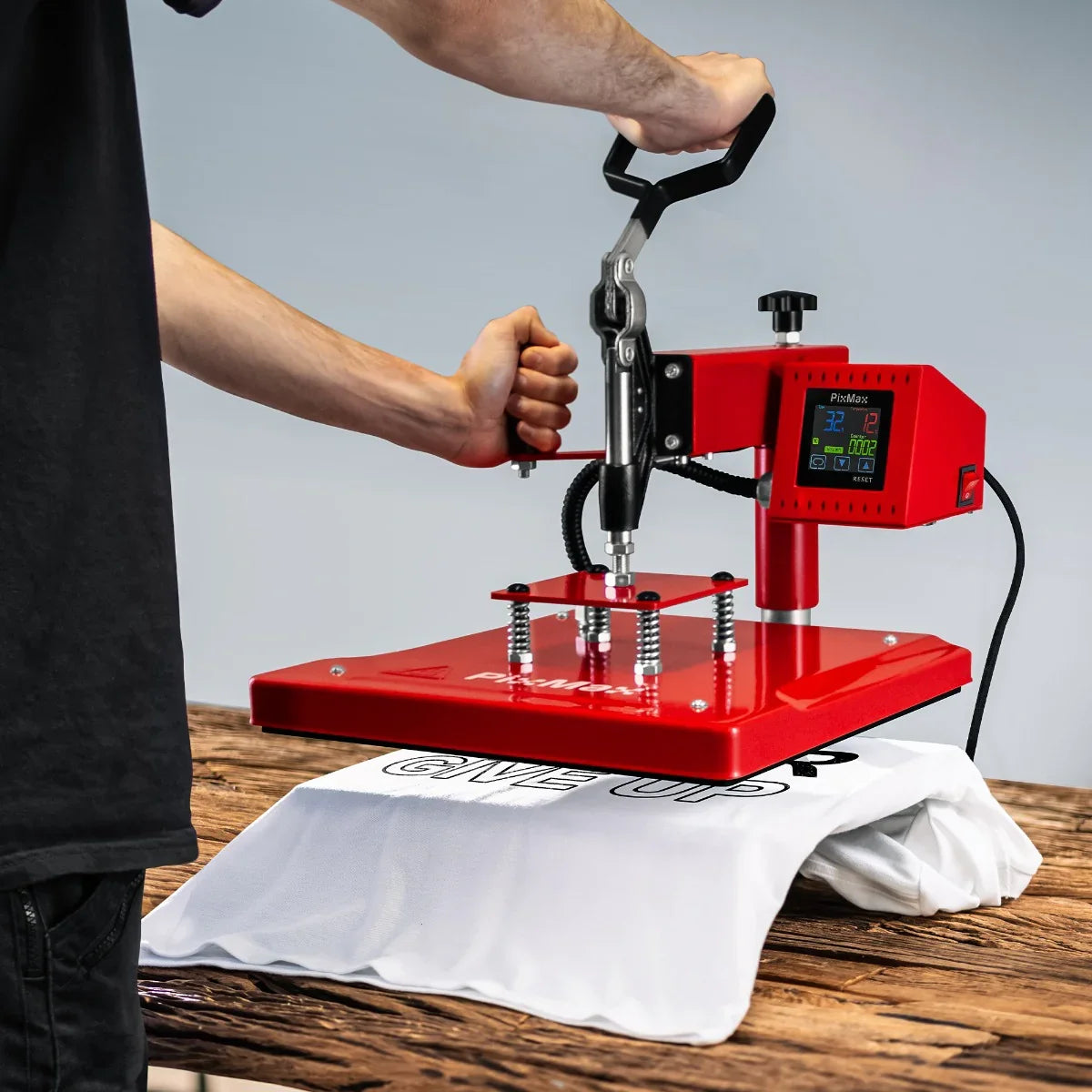 Swing Heat Press 38 x 38cm in red, pressing a white t-shirt with a graphic, featuring a digital display and adjustable pressure handle