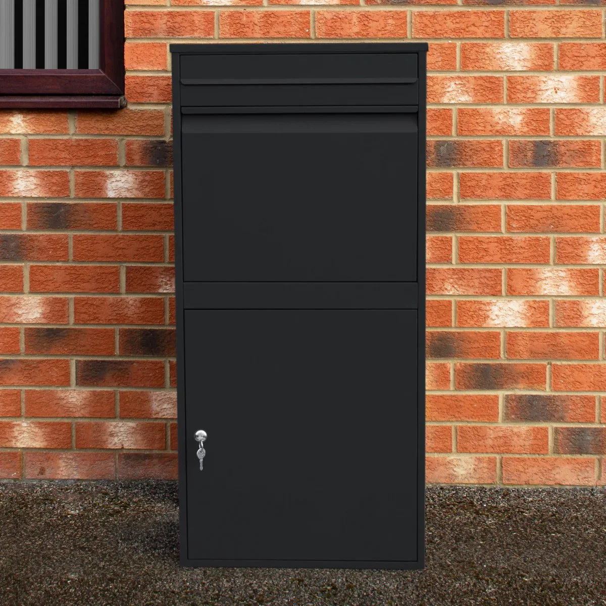 Black anti-theft parcel post box XL with a sleek design, sturdy metal construction, and secure locking mechanism against a brick wall