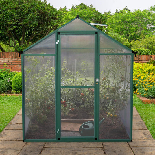 Greenhouse with transparent mesh walls, showcasing vibrant tomato plants inside, set on a stone patio surrounded by lush greenery