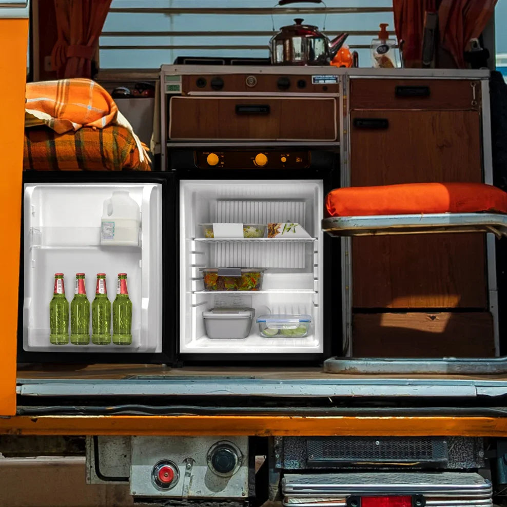 Compact 3-way absorption fridge with a sleek black exterior, showcasing drinks and food storage inside, set in a cozy van interior
