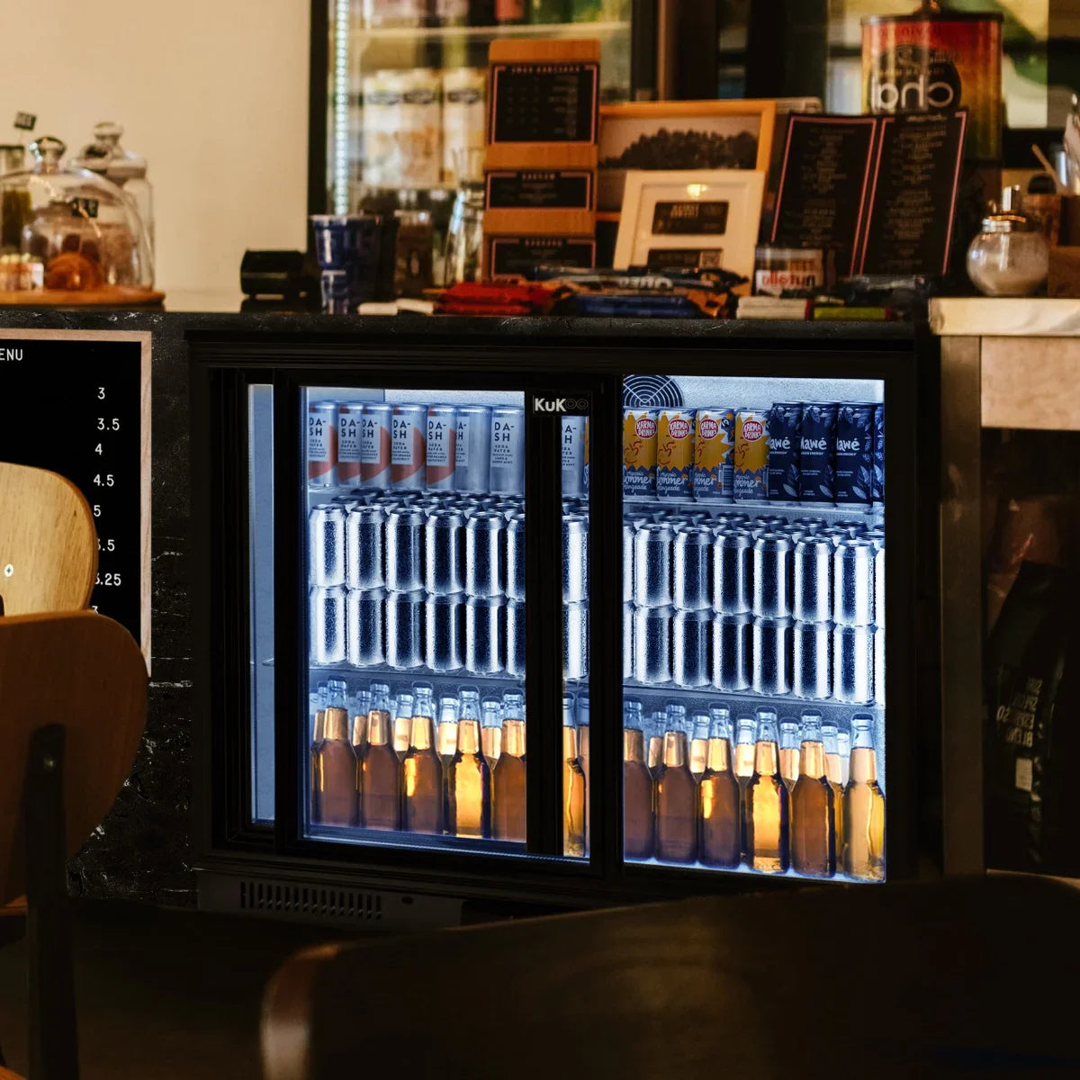Sliding double door back bar fridge cooler displaying a variety of beverages, including cans and bottles, illuminated for visibility