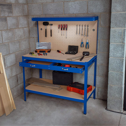 Blue metal workbench with tools, drawers, and pegboard, set against a gray concrete wall, ideal for DIY projects and organization