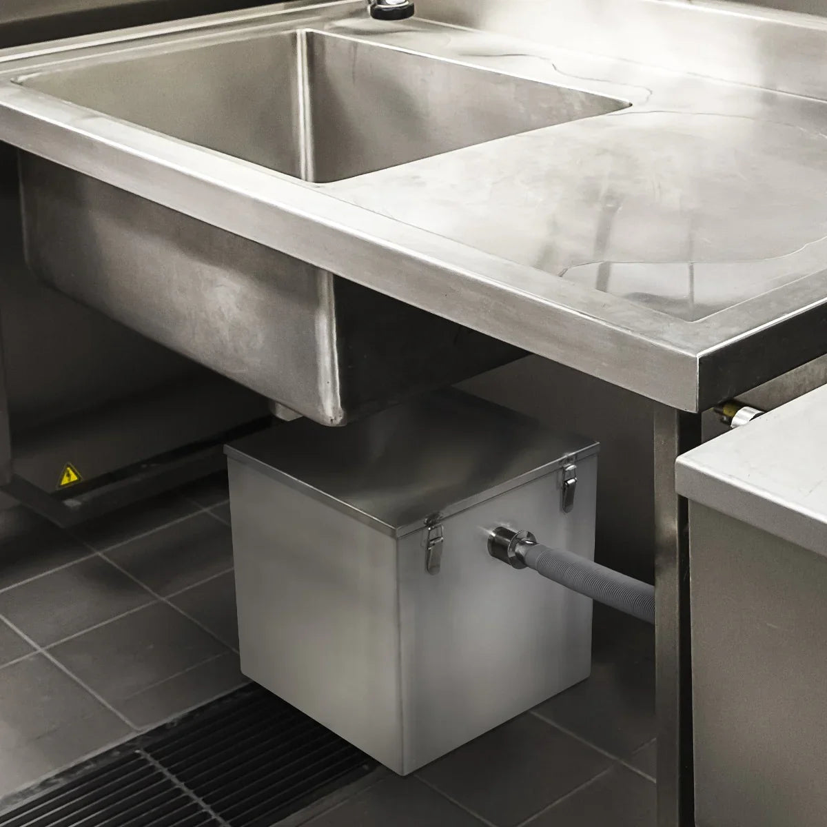 KuKoo 60-litre grease trap installed under a stainless steel sink, featuring a sleek design and durable metal construction