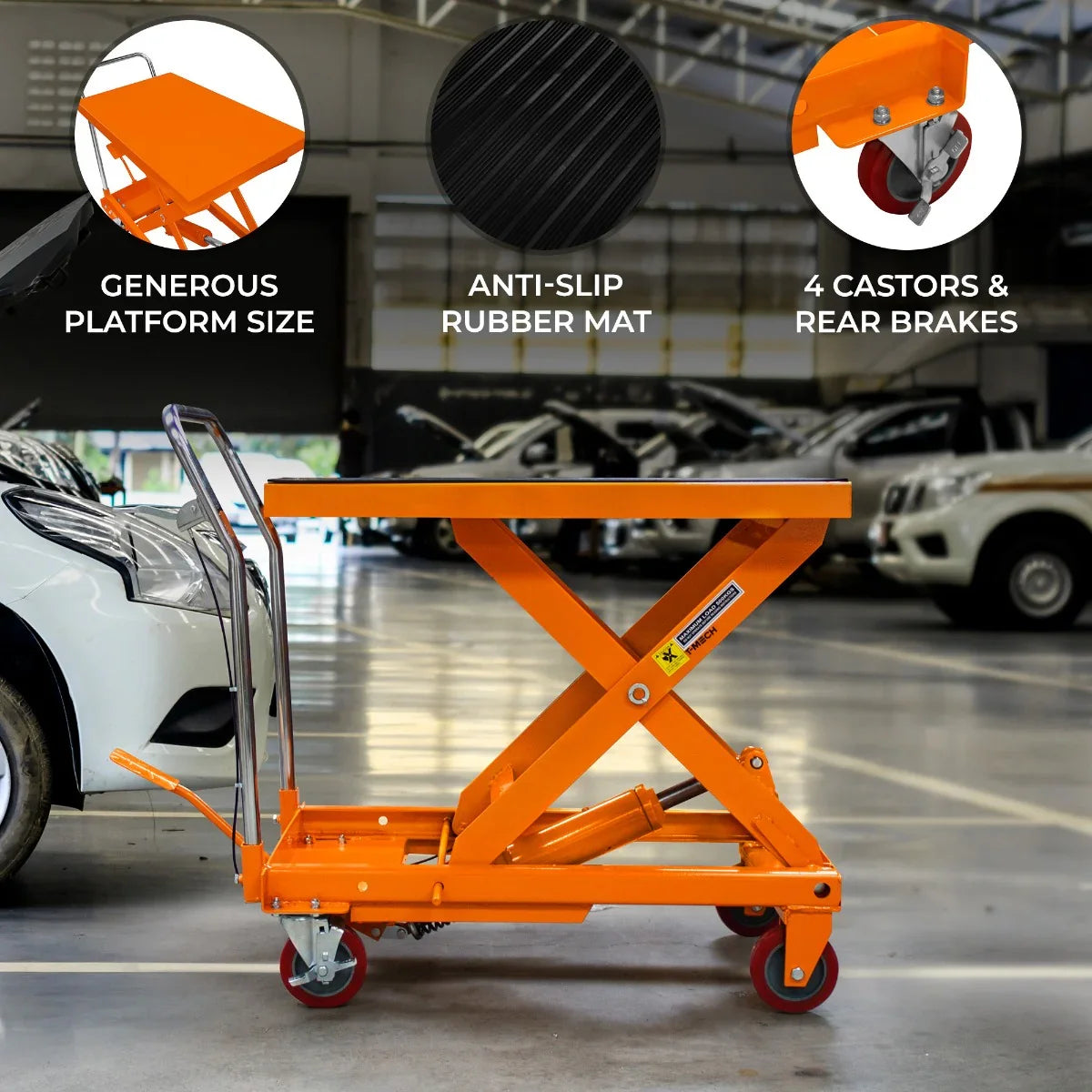 Hydraulic table lift in bright orange with a large platform, anti-slip rubber mat, four casters, and rear brakes in a garage setting
