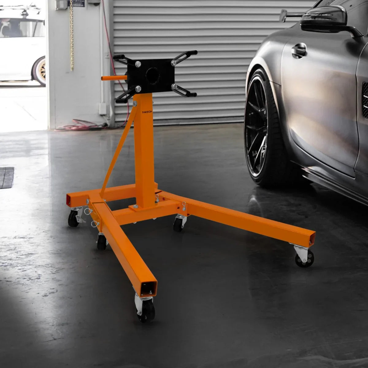 Folding engine stand in bright orange, featuring a sturdy frame, adjustable head, and smooth-rolling wheels for easy maneuverability