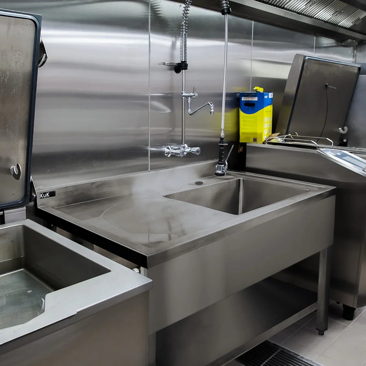 Stainless steel catering sink with left-hand drainer, featuring a polished surface, faucet, and spacious basin for efficient washing