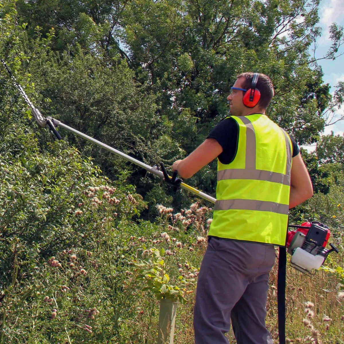 T-Mech 5 in 1 52cc petrol garden cutter multi-tool in use, featuring a man in a high-visibility vest trimming tall bushes with a pole saw