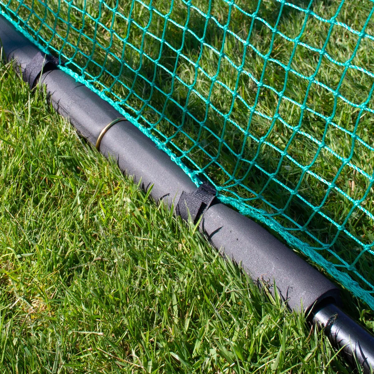 Durable golf practice cage net with vibrant green mesh, featuring a sturdy black support base resting on lush grass