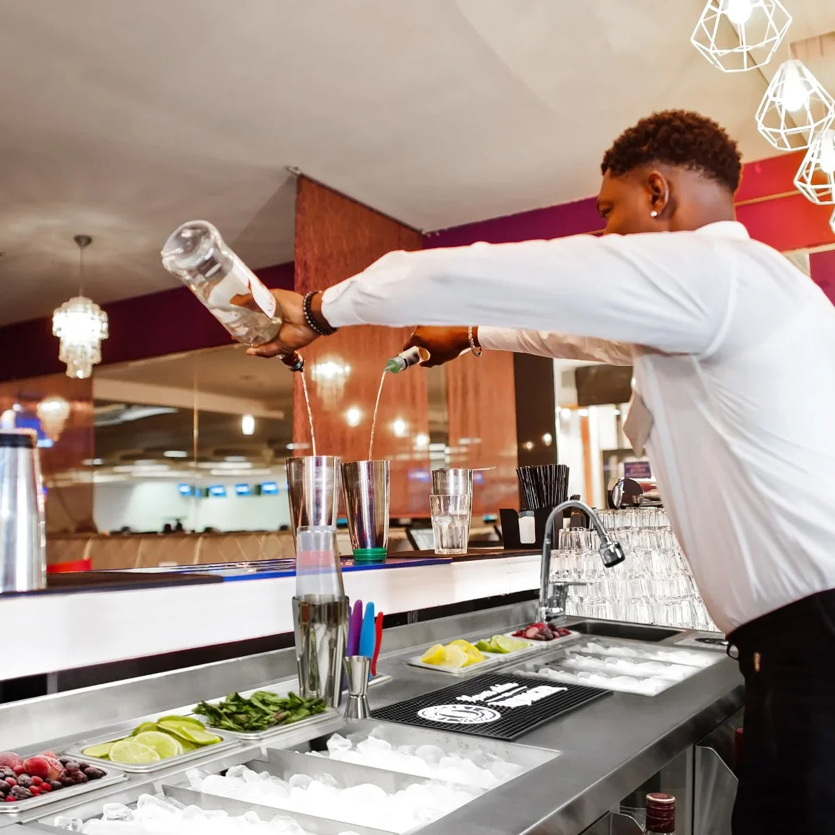 Twin Cocktail Bar Station with a bartender pouring drinks, featuring fresh ingredients like limes, mint, and ice in a sleek stainless steel design
