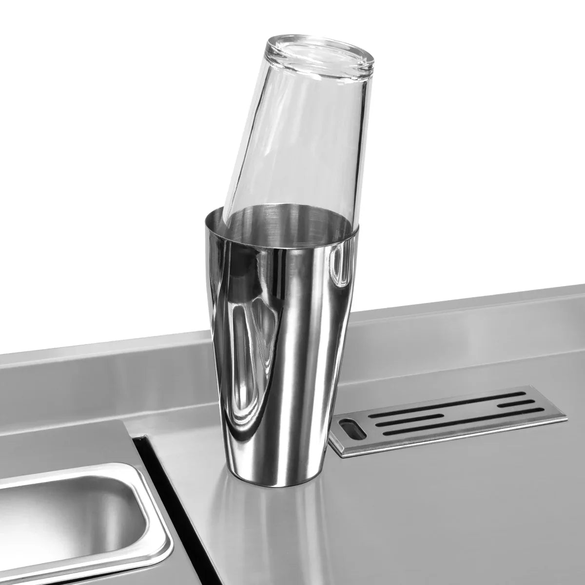 Stainless steel cocktail shaker with a glass resting inside, showcasing sleek design and modern bar station elements