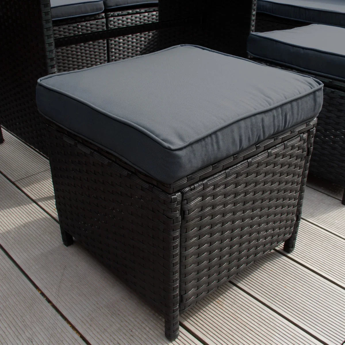 Black rattan corner set featuring a plush, dark gray cushion on a woven wicker base, perfect for outdoor lounging and relaxation