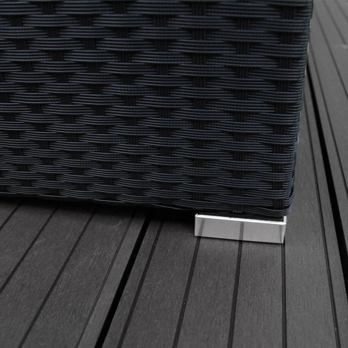 Black rattan corner set featuring a textured weave and sleek metal feet, positioned on a dark wooden deck surface