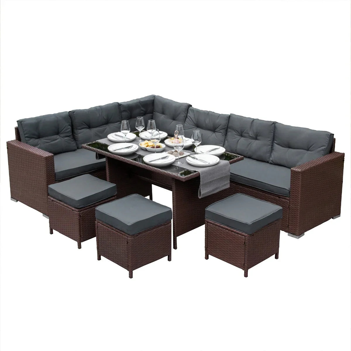 Brown rattan corner set featuring plush gray cushions, a glass-topped table, and matching ottomans, perfect for outdoor dining